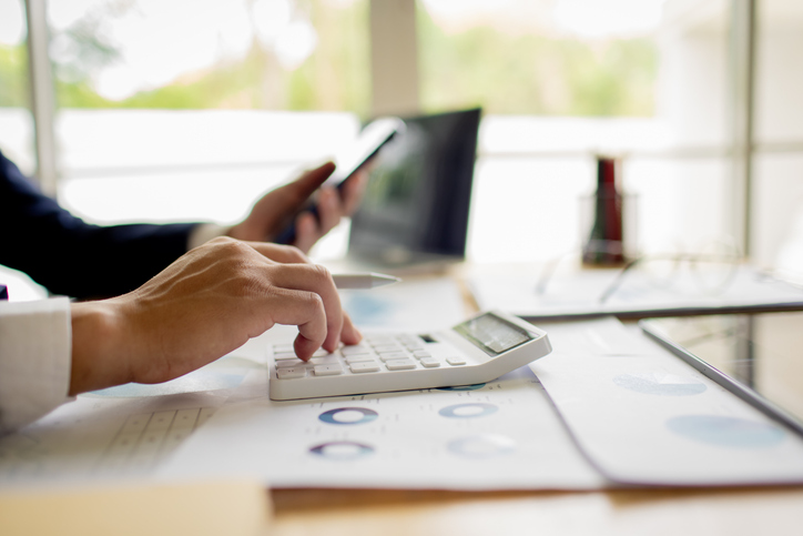 person using a calculator to budget and analyze tax strategy - can you accidentally commit tax fraud?