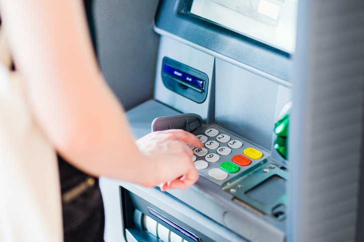 Person using an ATM at a bank - how does money laundering affect the economy?