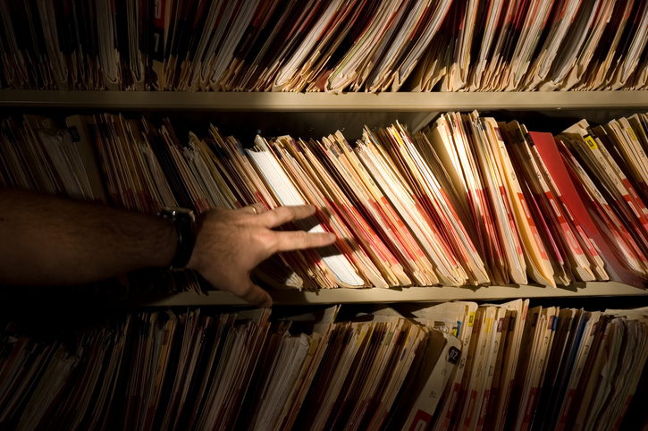 pointing in front of a bookshelf of medical records - the most common healthcare fraud schemes prosecuted in recent years | Griffin Durham